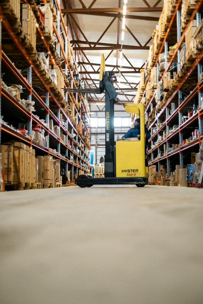 A reach truck in a warehouse aisle lined with stocked racking. A reach truck in a warehouse aisle lined with stocked racking.